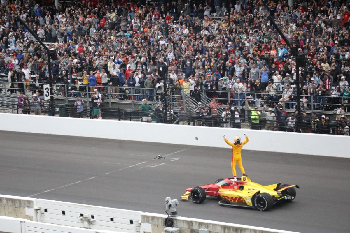 Alex Palou stands on his vehicle to the cheers of the crowd after winning the 109th running of the Indianapolis 500.