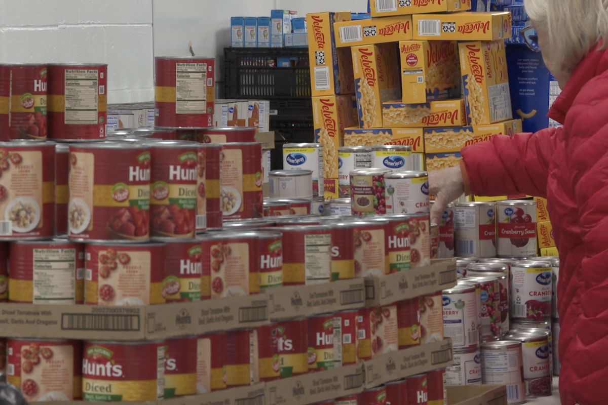 A woman grabs canned cranberry sauce at Pantry 279's Thanksgiving food distribution.