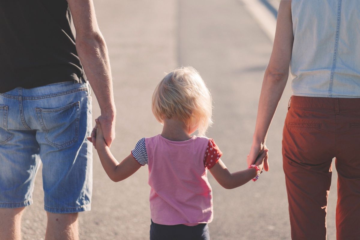 A child holding the hands of two adults (parents, divorce, parenting, kids).