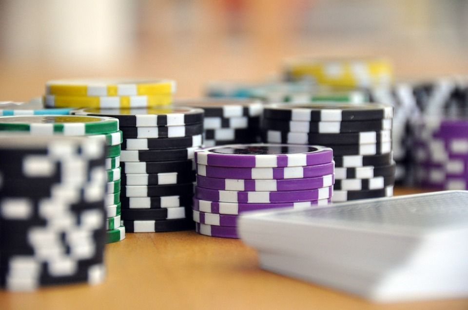 Gambling chips sit stacked on a table next to a deck of playing cards.