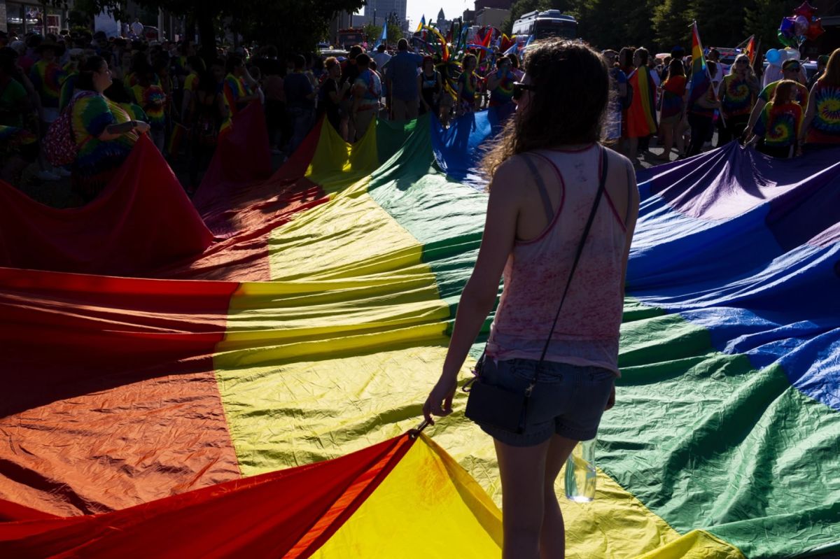 Parade participants hold a large rainbow Pride flag as they wait for the parade to begin.