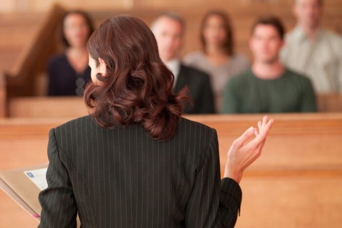 Public defender facing a group of people seated in a courtroom.