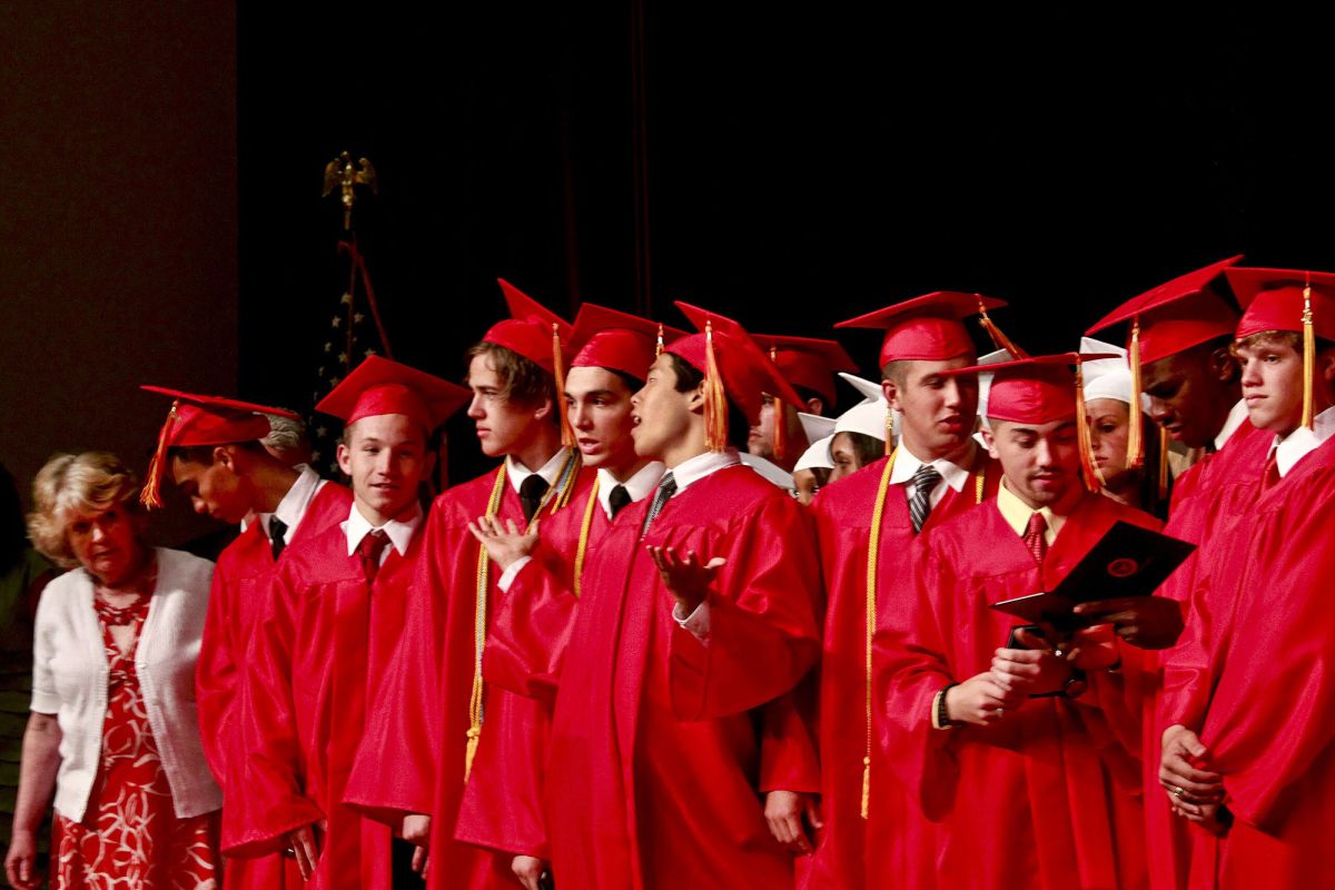Group of high school graduates in red caps and gowns