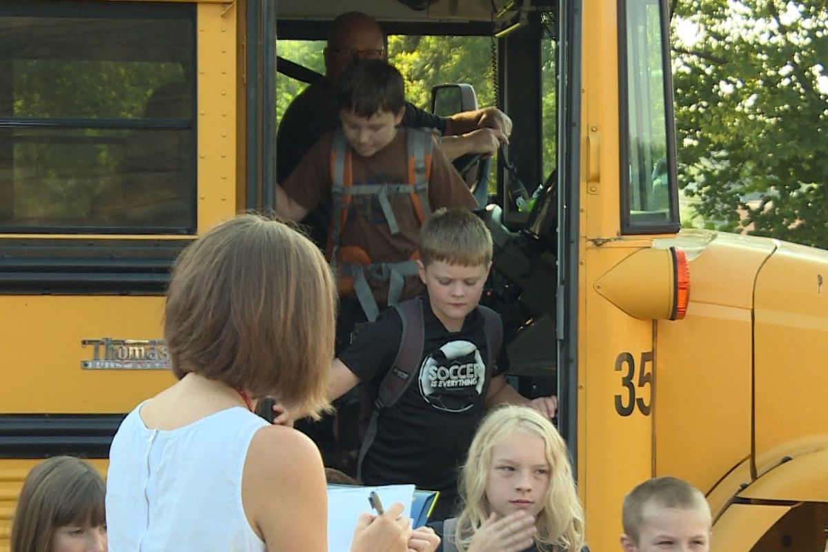 Children are getting off of a school bus. 