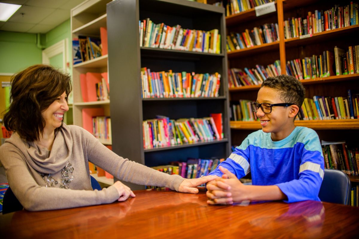 school counselor talks to student in library