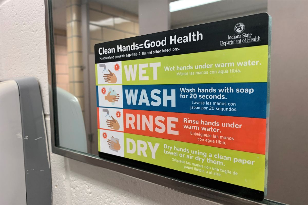 An Indiana University sign advising people about washing their hands and maintaining cleanliness in bathrooms.
