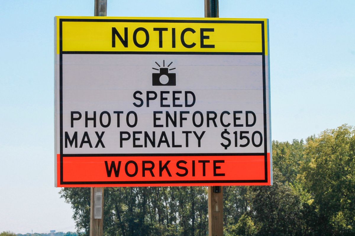 A road sign reads "Notice Speed Photo Enforced. Max Penalty $150. Worksite"