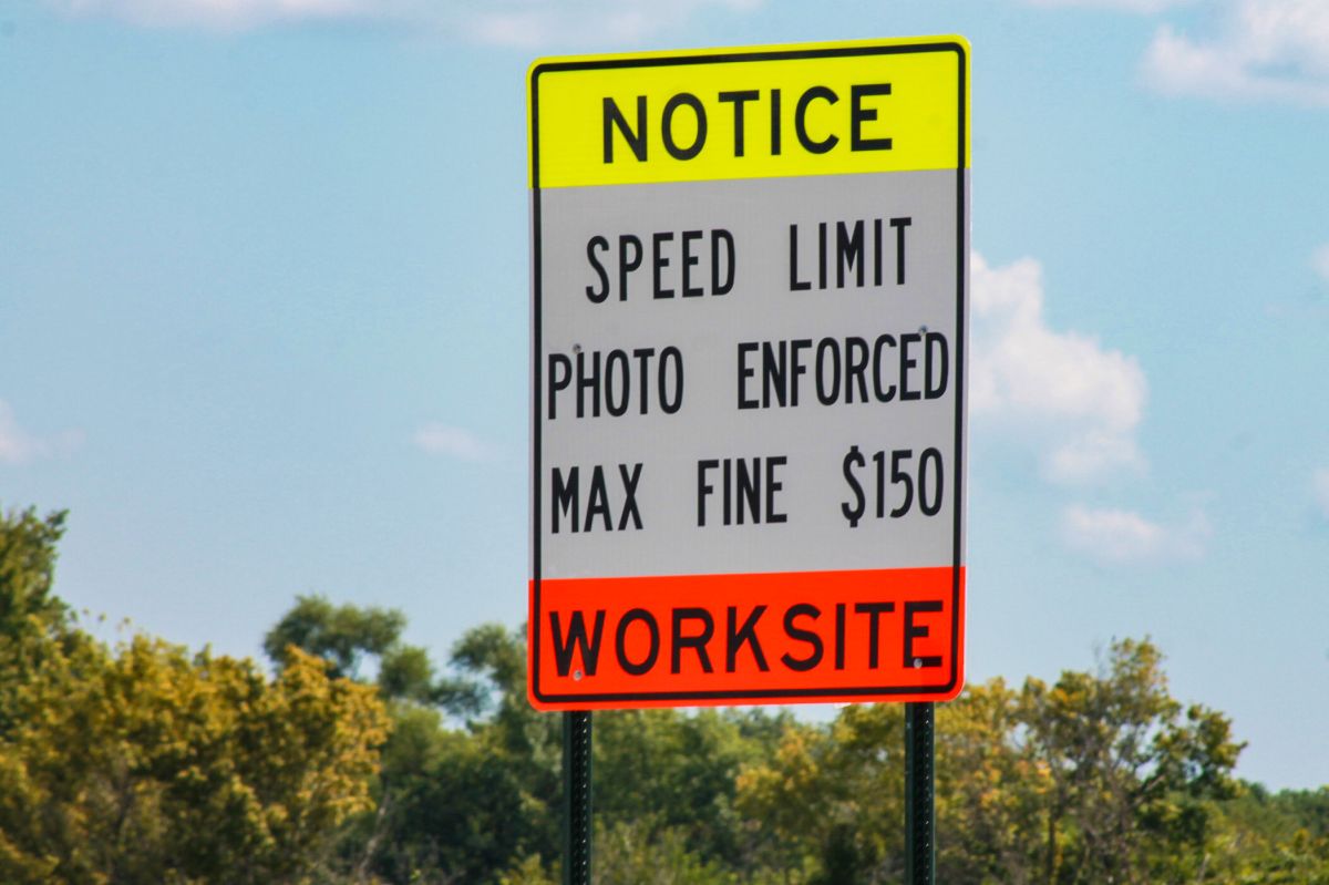 A road sign that reads "Notice Speed Limit Photo Enforced Max Fine $150 Worksite"