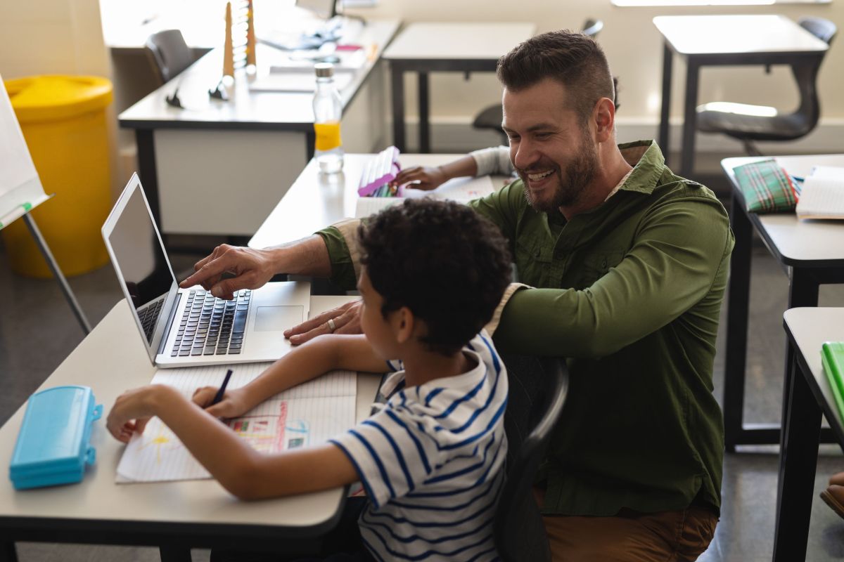 teacher helping boy study on laptop