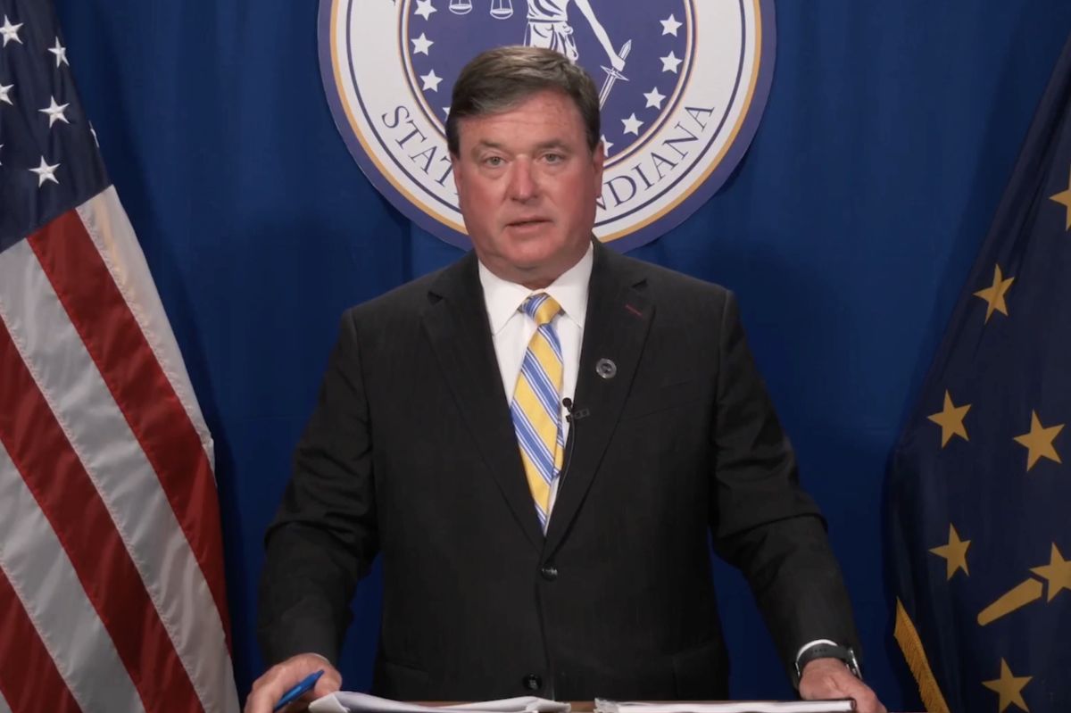 A screenshot of a Facebook Live shows Todd Rokita standing at a lectern in front of the American and Indiana flags, with the seal of the office of the attorney general behind him.