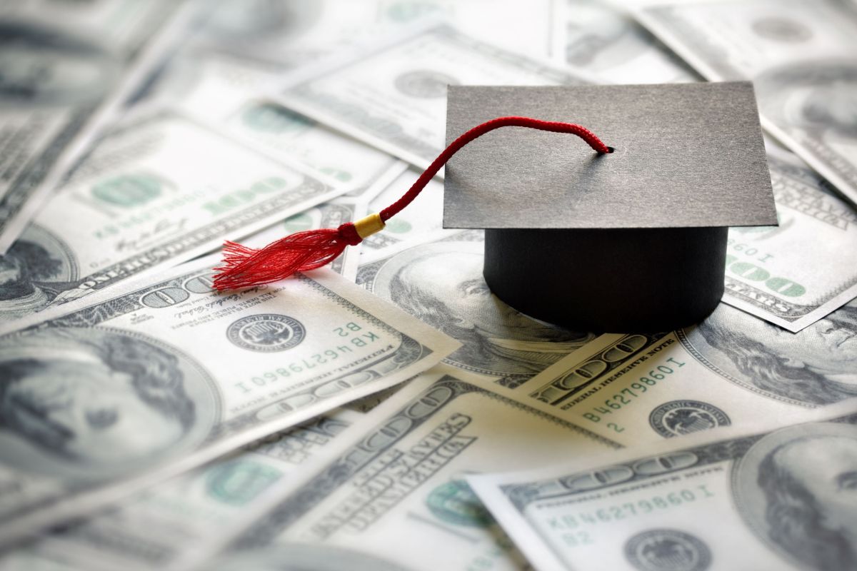 tuition stock image of paper graduation cap on top of $100 bills