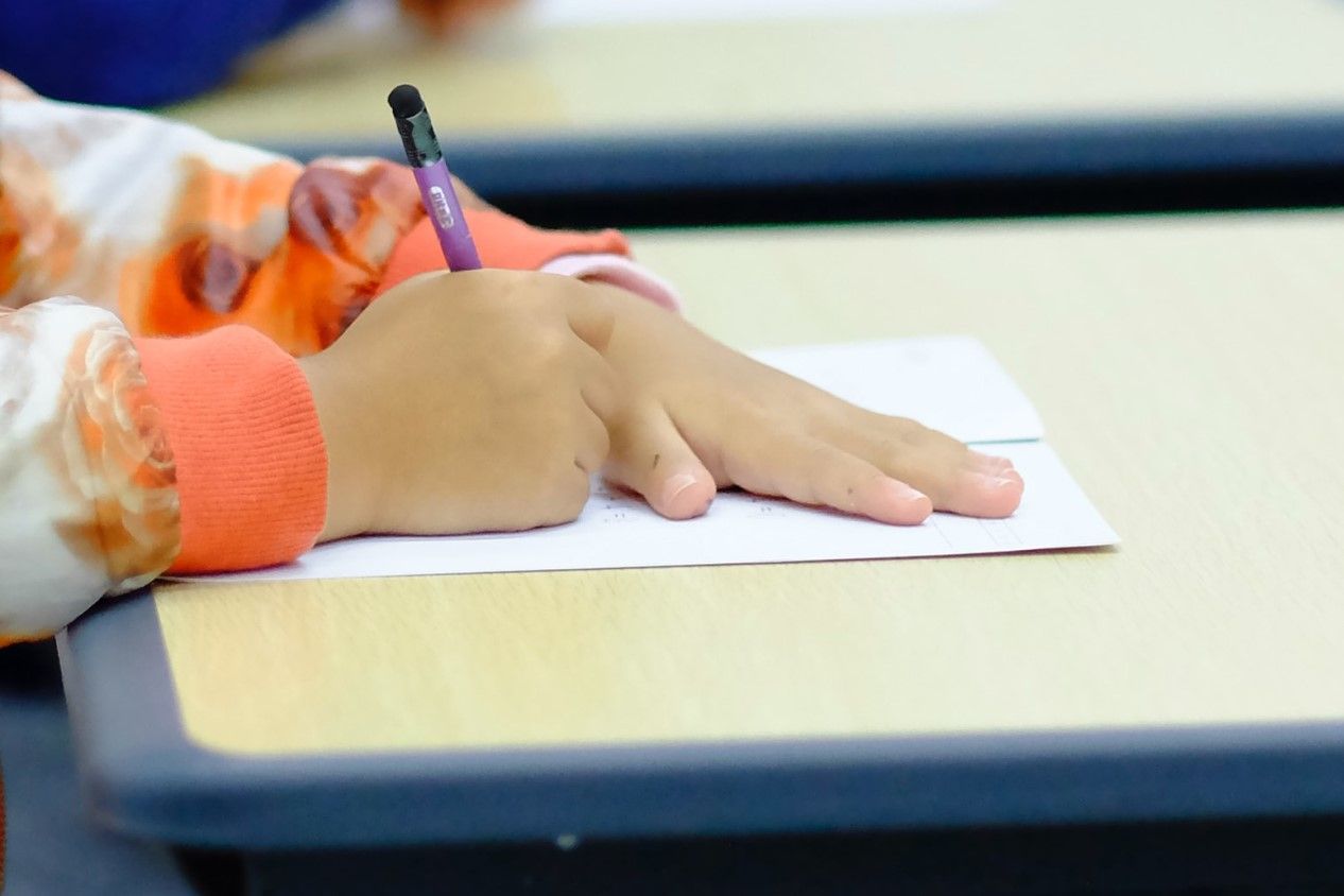 a student writes on a piece of paper at a desk