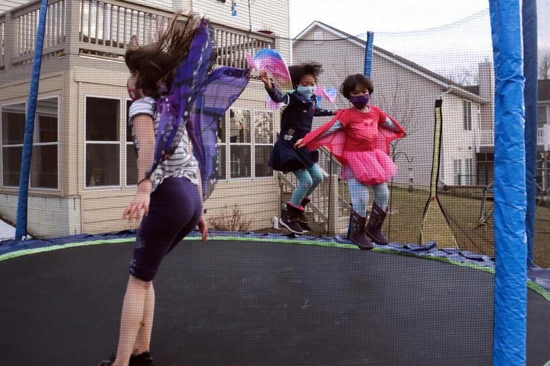 Kids wearing masks jumping on a trampoline.