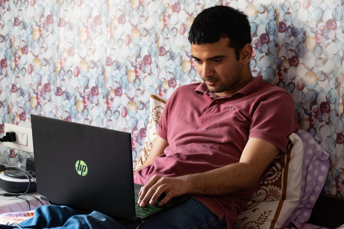 A stock image of a man working from home in bed.