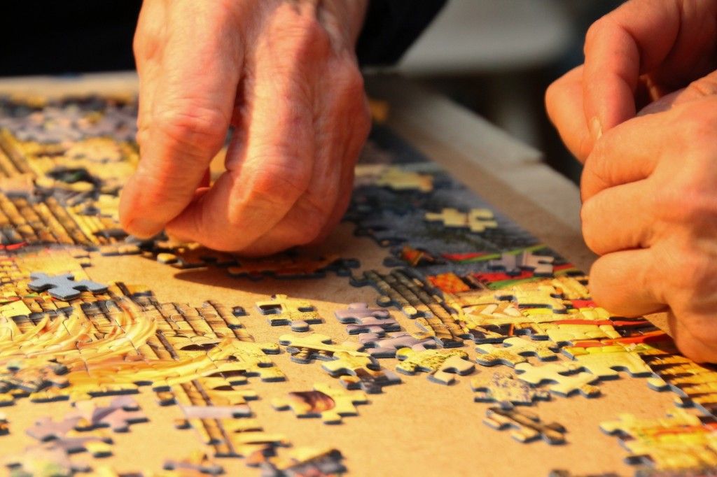 Peoples' hands putting together a jigsaw puzzle