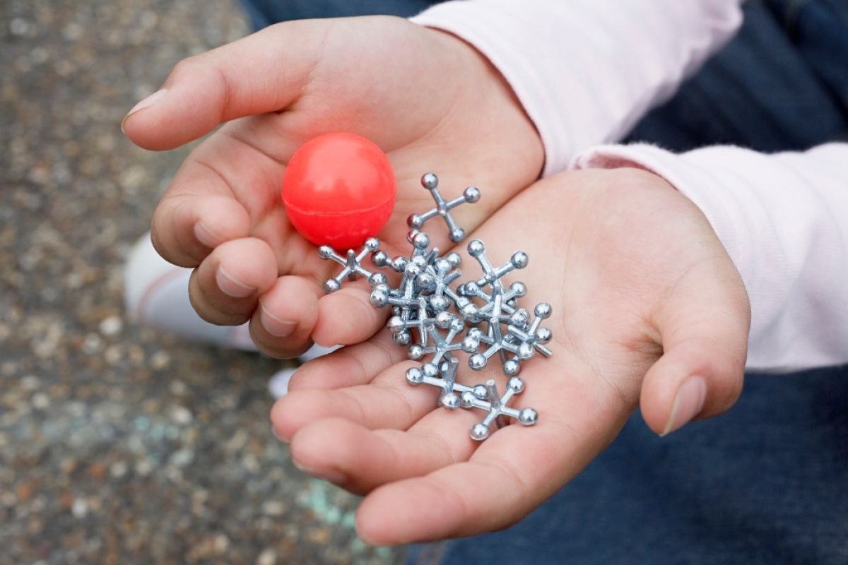 Child's hands holding ball and jacks.