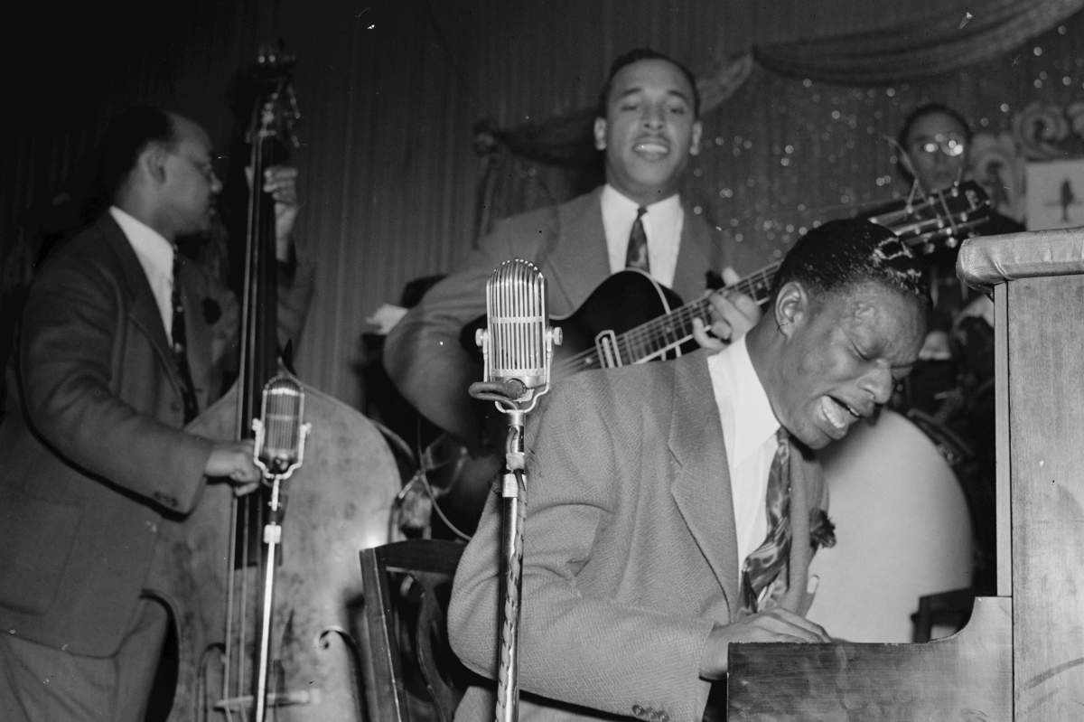 Portrait of The King Cole Trio (l–r., Wesley Prince on bass, Oscar Moore on guitar, and Nat King Cole on piano) performing at Zanzibar in New York, N.Y., ca. July 1946.