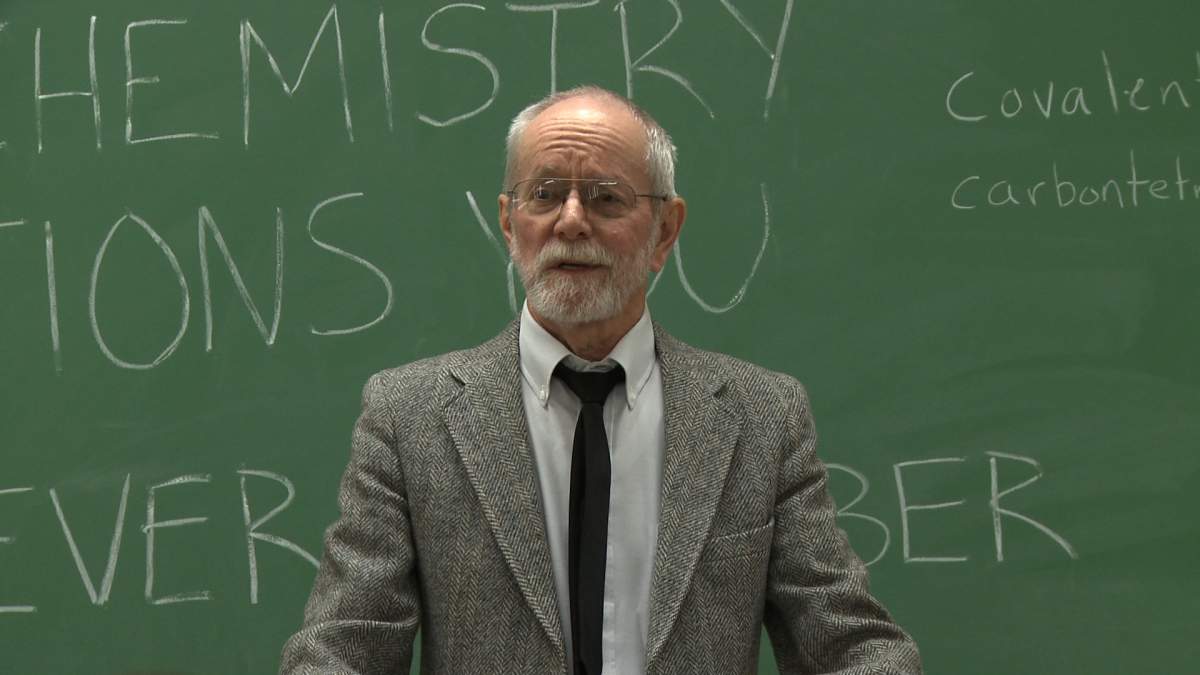 A professor standing in front of a chalkboard