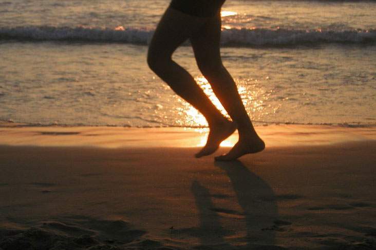 legs running on the beach at sunset