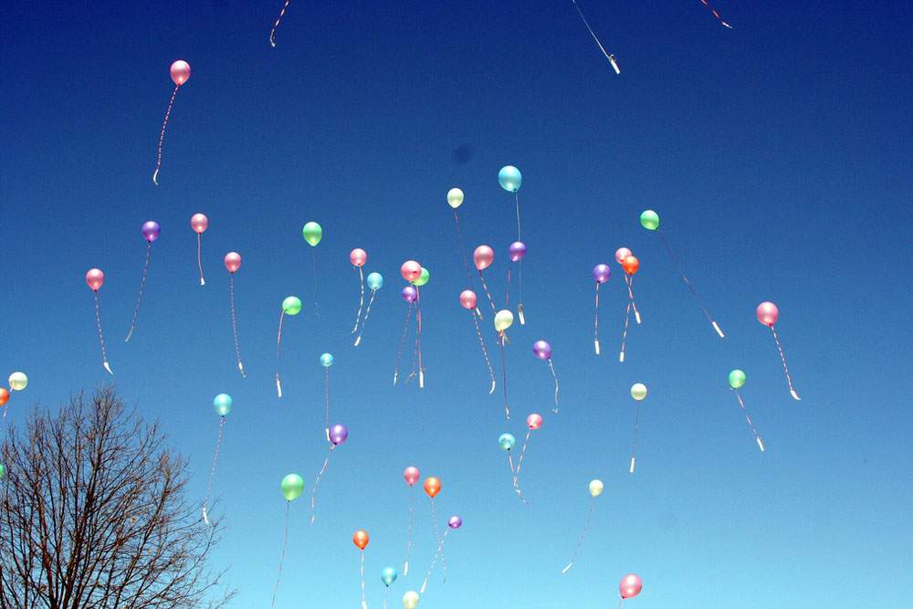 a large group of balloons floating into the air