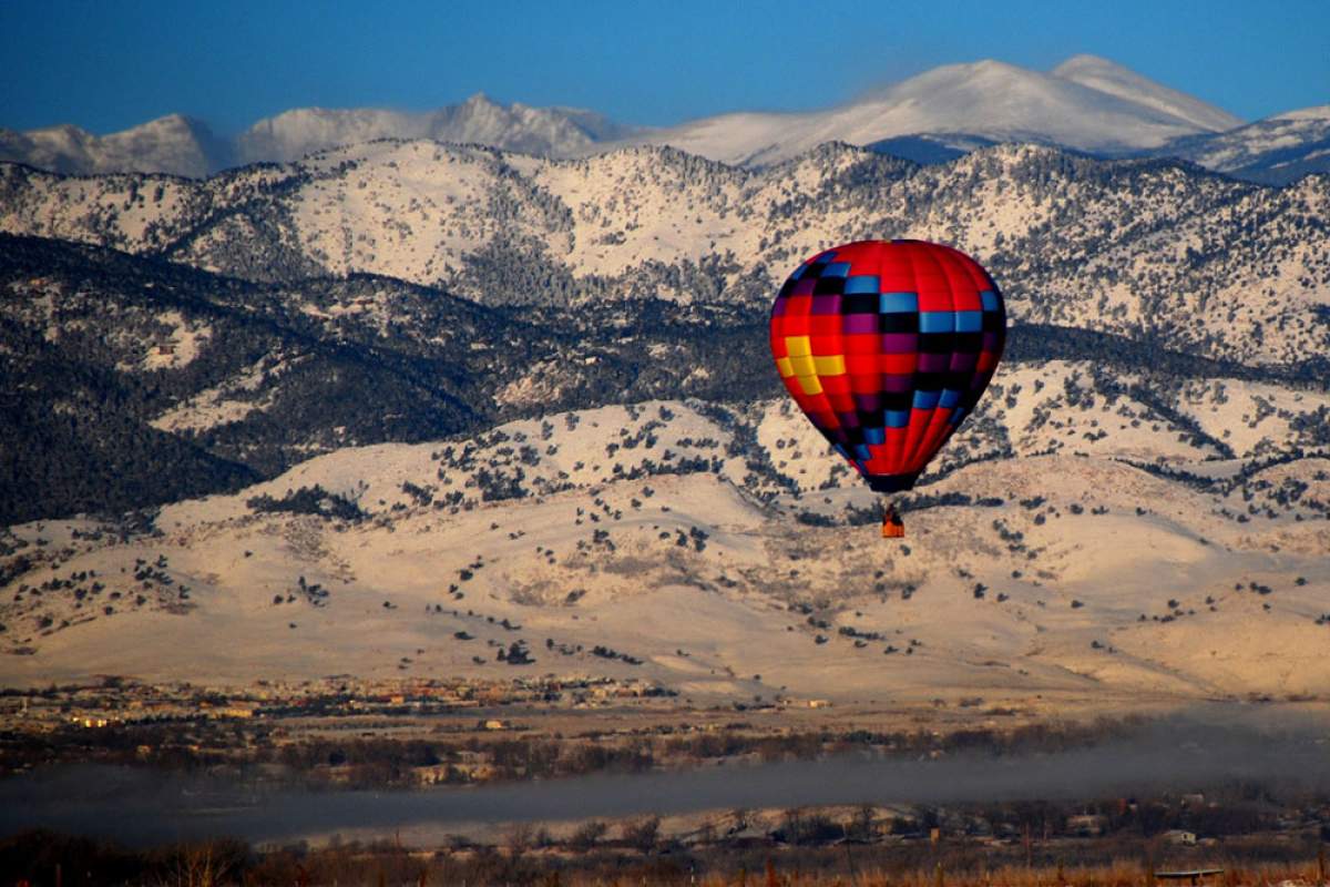 a hot air balloons flys past a snowy mountain