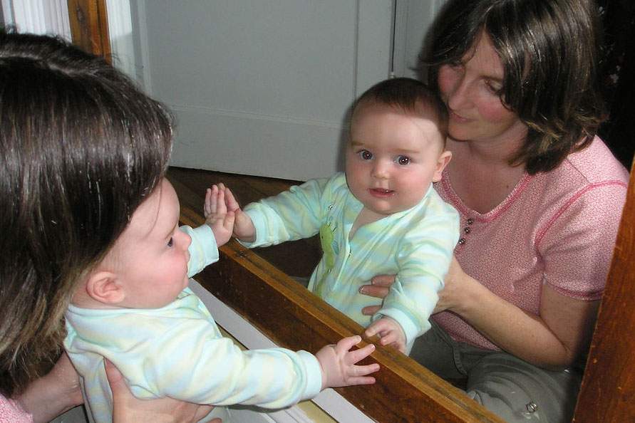 a baby looking in the mirror
