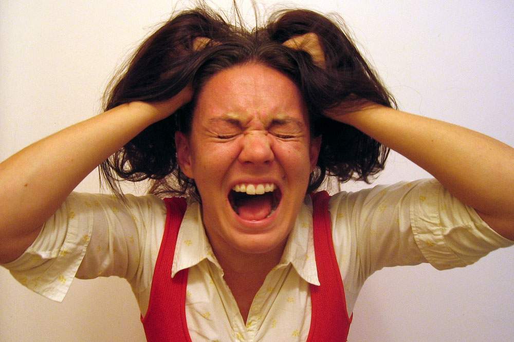 a woman yelling and tugging her hair