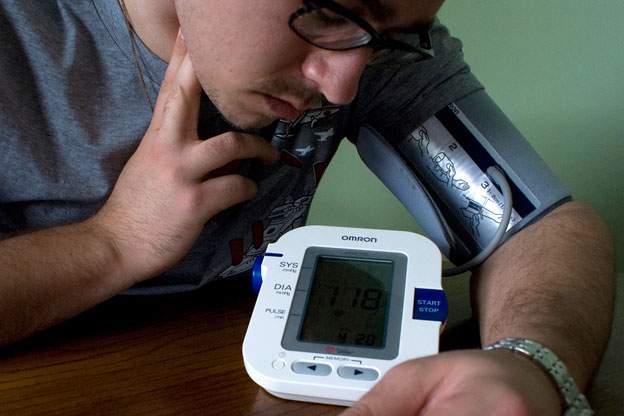 a man checks his pulse while using a blood pressure monitor