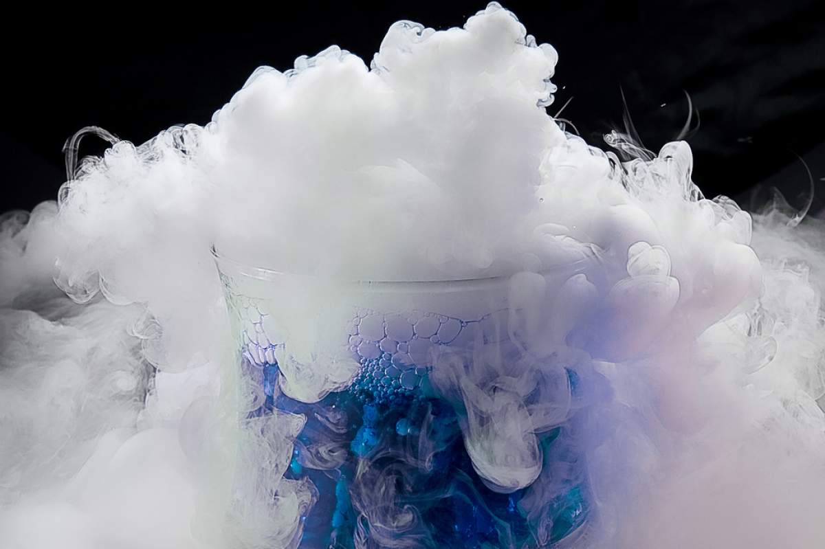 Dry ice sublimating from a glass with blue liquid
