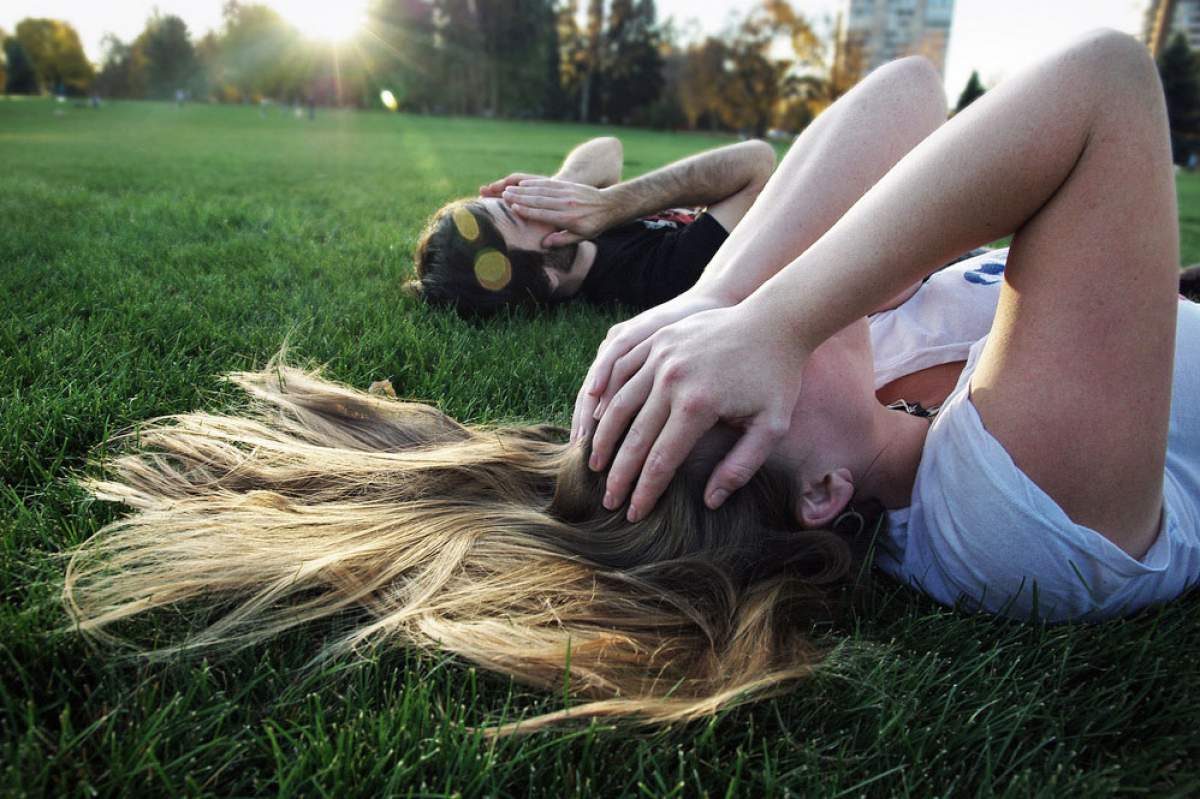 two people laying in the grass with their hands over their eyes
