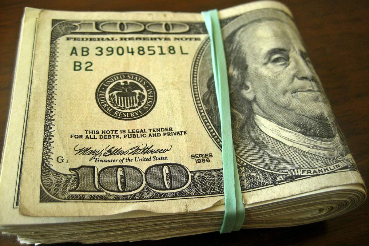 100 dollar bills tied together with a green rubberband