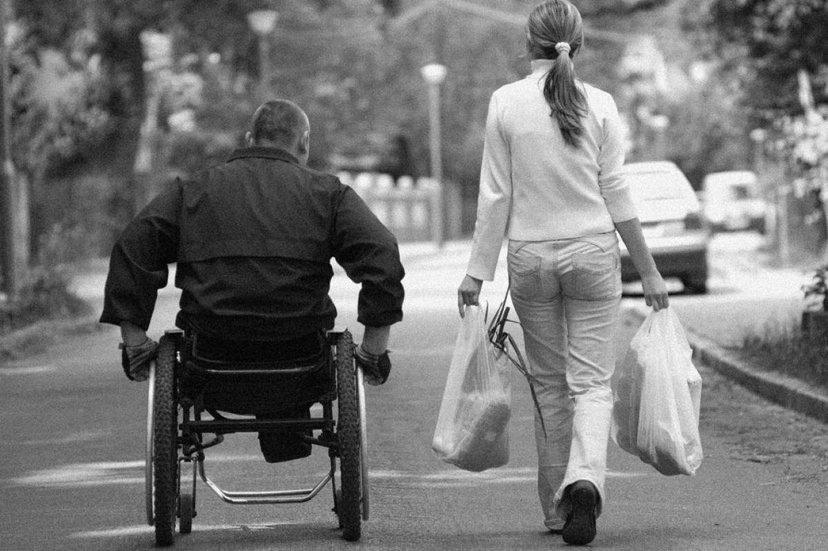 man in wheelchair and woman walking beside him