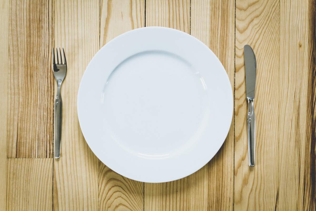 white plate on wooden table with fork and knife surrounding