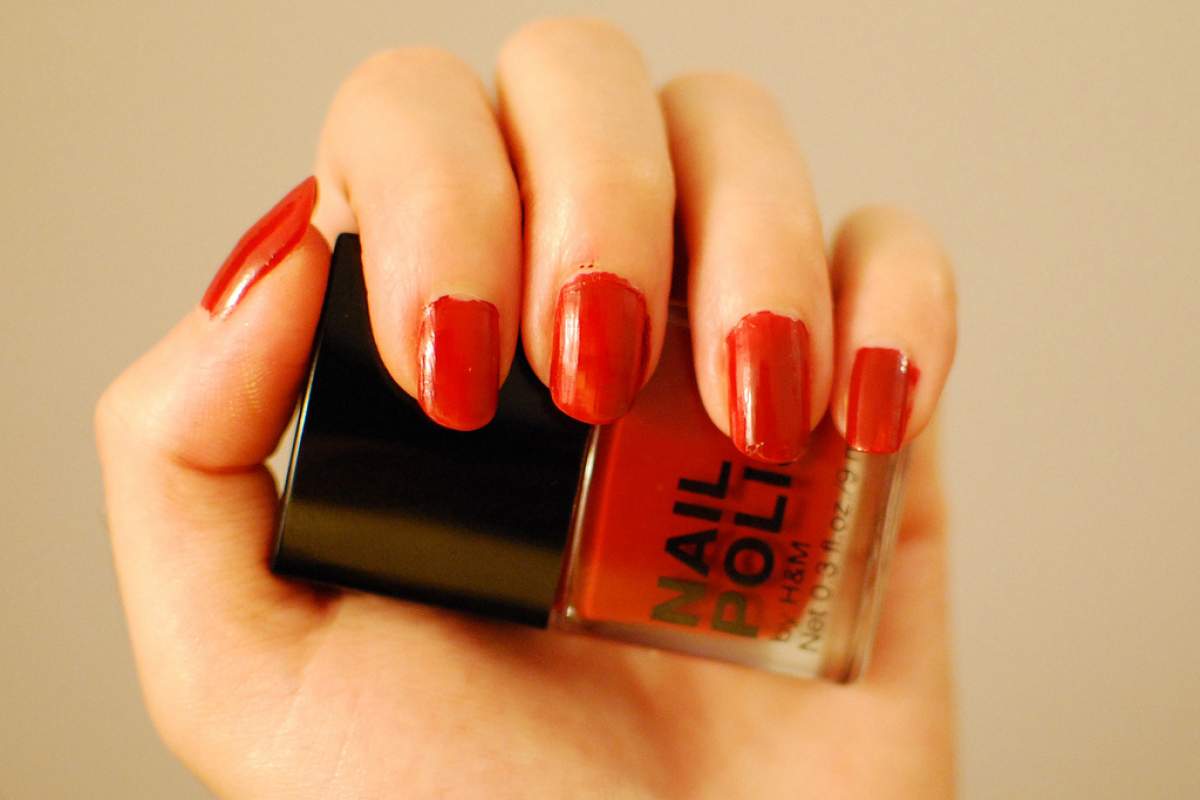 hand holding bottle of red nailpolish with nails painted red