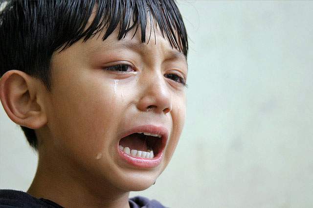 boy crying against a gray background