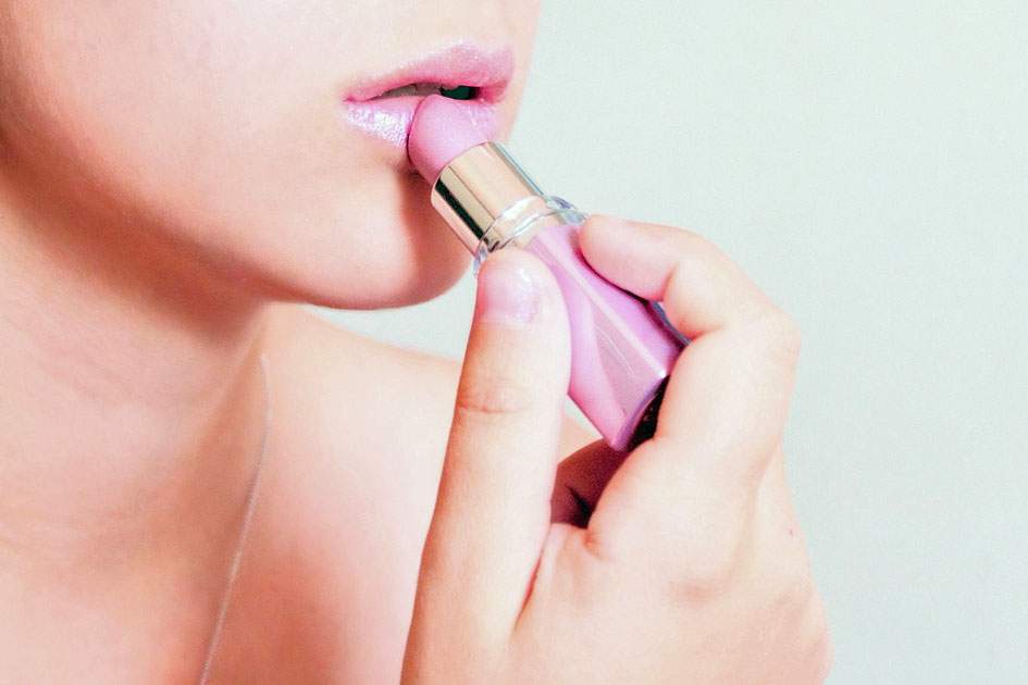 woman putting on pink lipstick