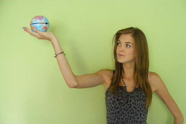 woman holding a small earth in her hand against a green background