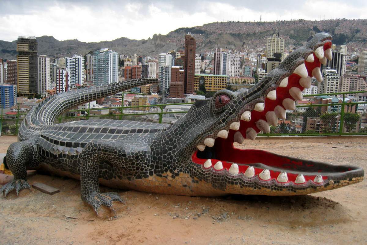 A giant alligator sculpture foregrounds a cityscape.