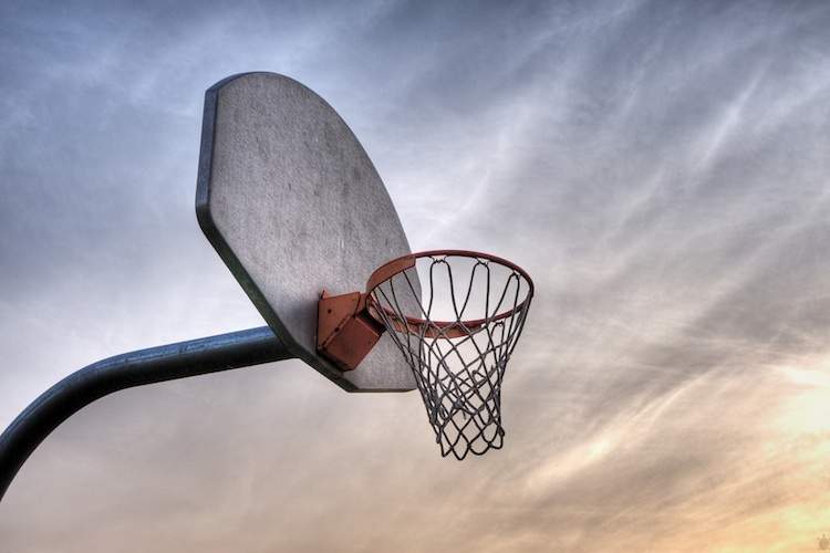 An outdoor basketball hoop at sunset