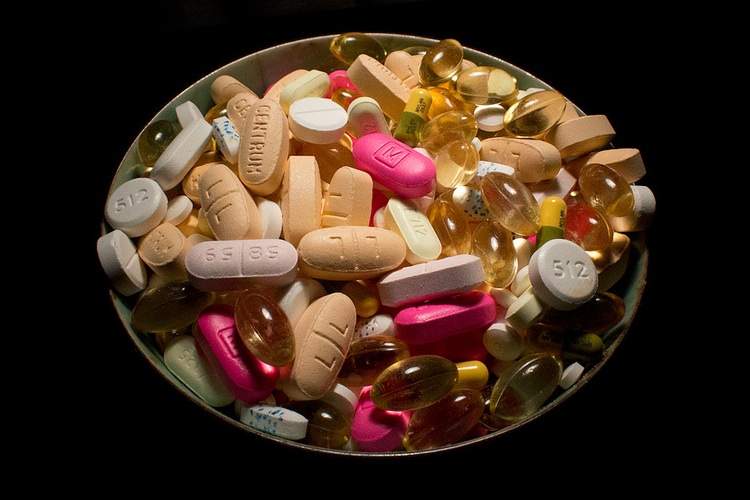 A bowl of multi-colored vitamins against a black background