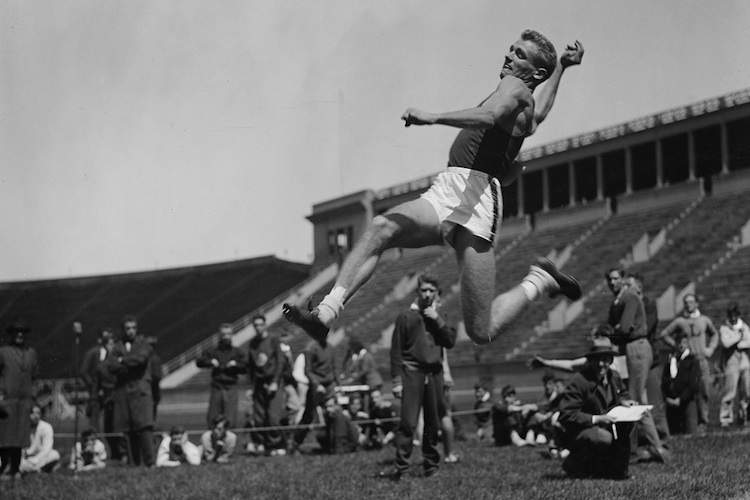 Black and white photograph of a long jumper in mid-flight.