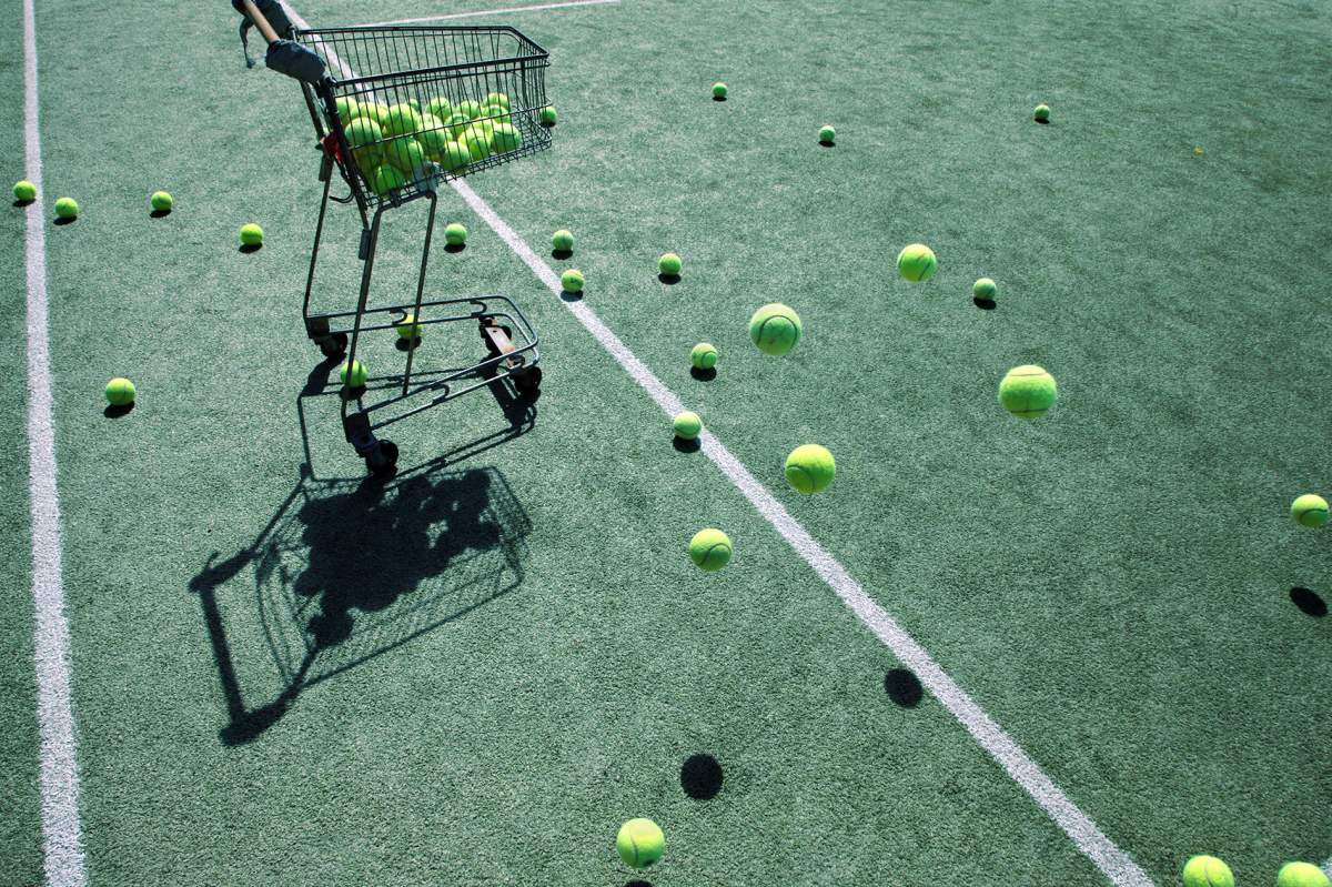 A cart full of tennis balls on a tennis ball court