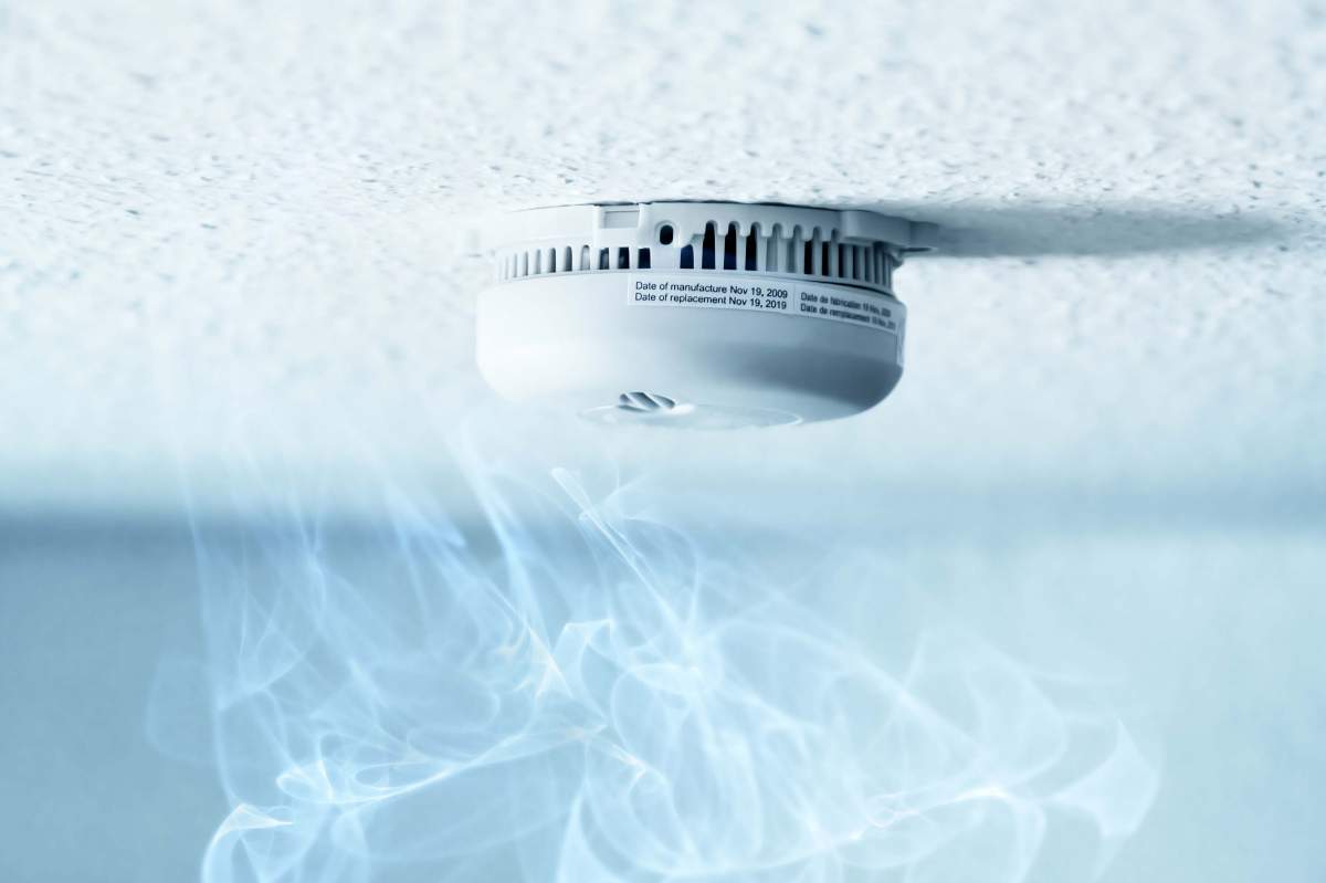 a smoke alarm attached to ceiling with rising smoke/steam