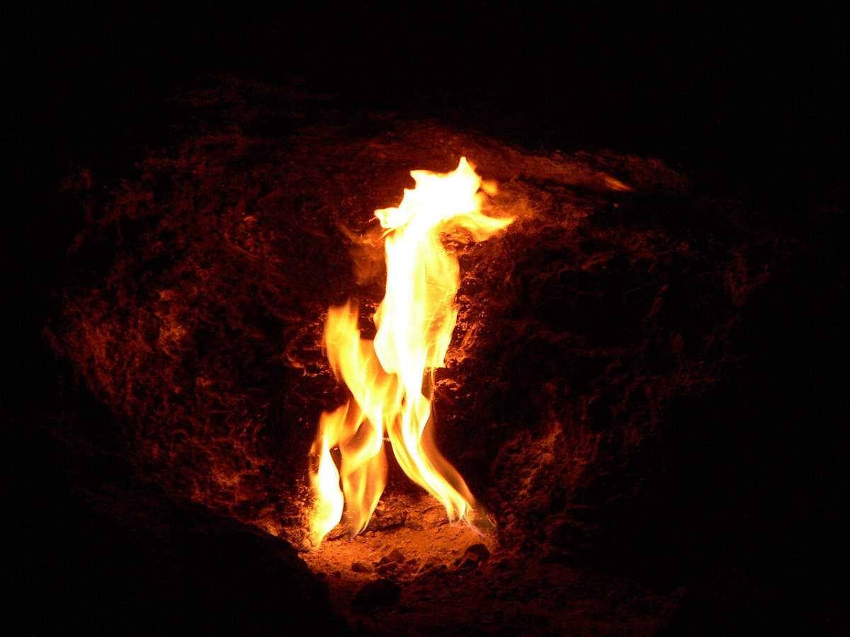 A fire lights up a rocky hole.