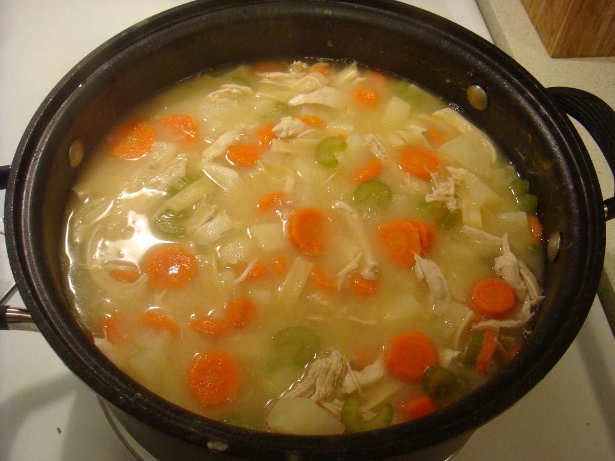 Pot of chicken noodle soup with carrots, noodles, and celery.