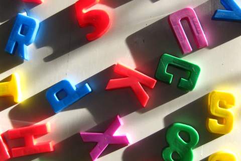 Brightly colored alphabet and number refrigerator magnets pointed in different directions.