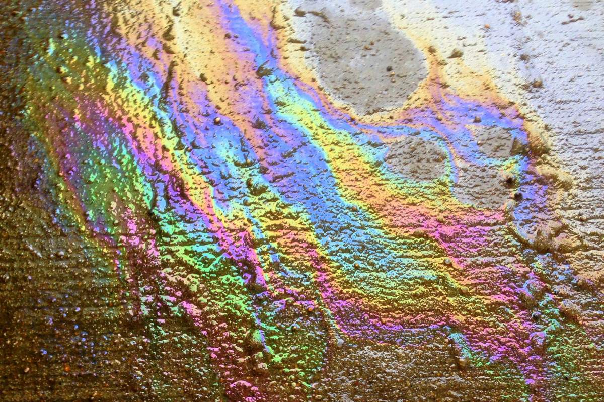 Gasoline spilled on concrete. The spilled gasoline is iridescent, so it looks like a smashed up rainbow.