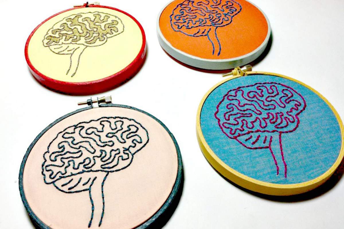 4 hand-stitched images of brains. The top left is yellow, the top right is orange, the lower right is bright blue, and the lower left is mauve.