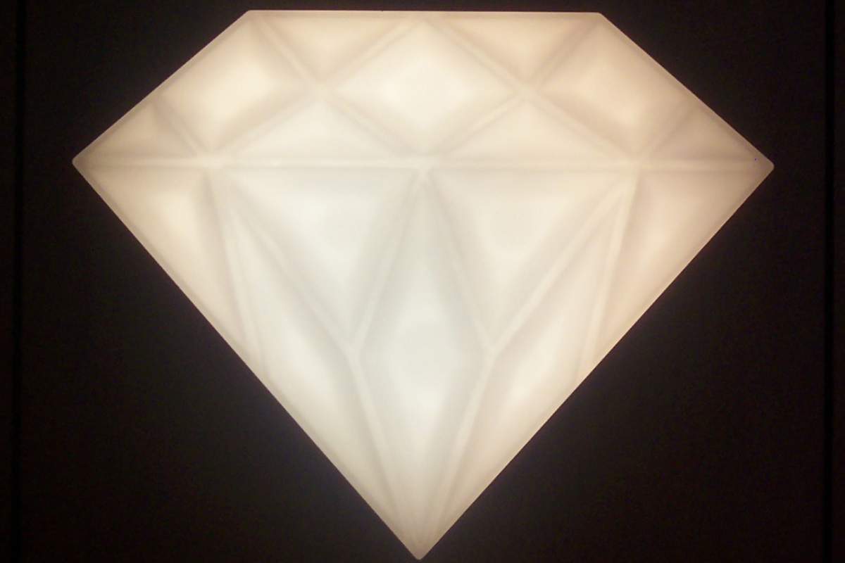 A drawing representation of a diamond. The diamond is white. The background is black.