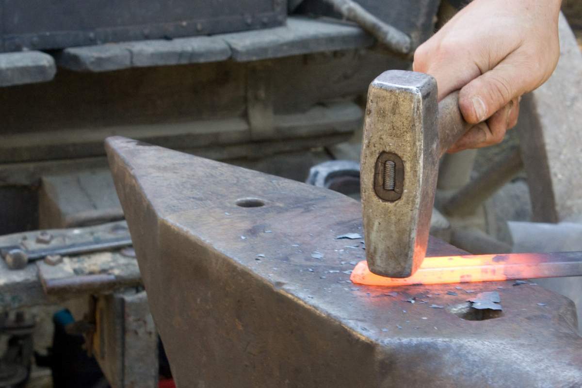 A close-up on a hammer hitting heated up metal on an anvil.